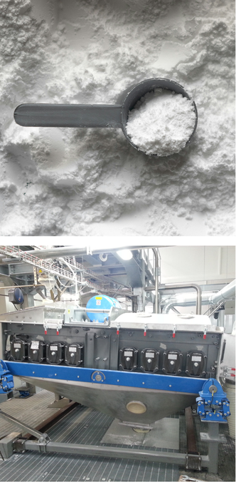 Tartaric acid powder scoop above an industrial vibrating sieve classification system