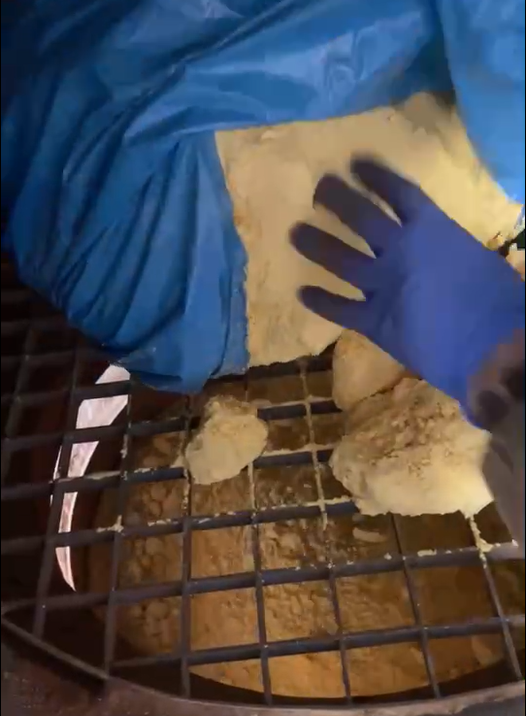 Operator emptying a full bag of powder in one go onto a vibro-sieve grid, creating a load peak