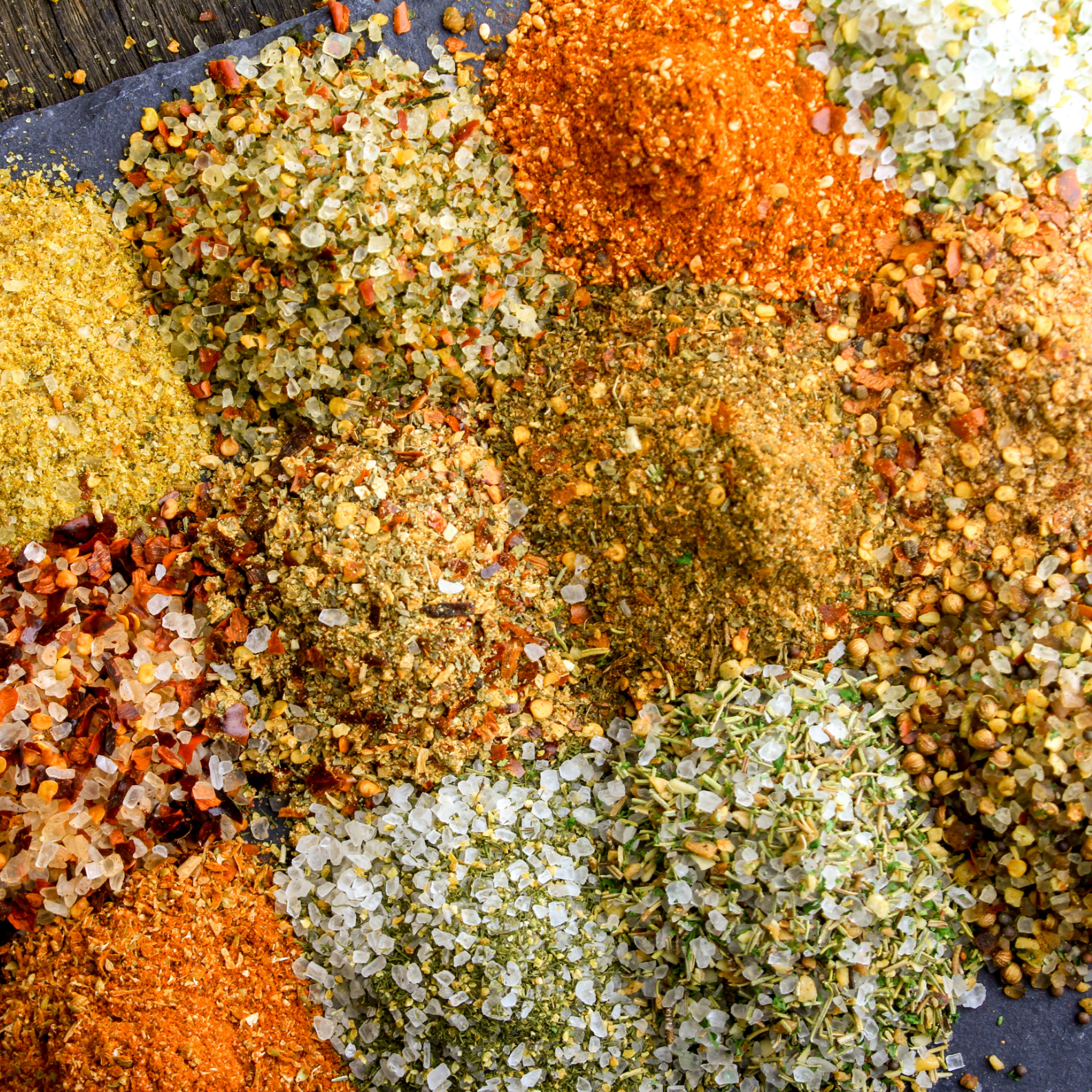 multiple blends of coarse salt crystals, dried herbs, spices and chilli flakes showing varied granulometry and particle size distribution